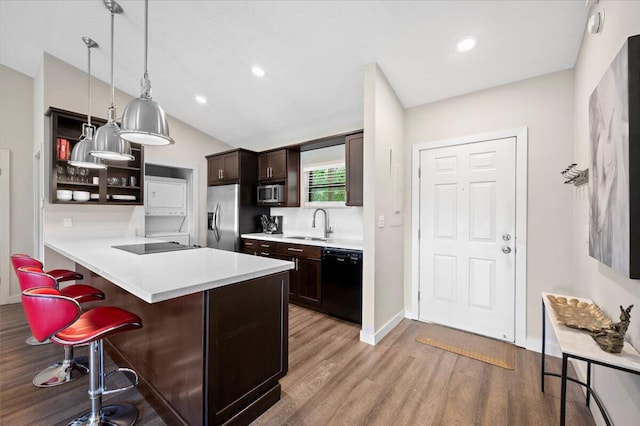 kitchen featuring stainless steel appliances, a kitchen breakfast bar, light hardwood / wood-style floors, lofted ceiling, and decorative light fixtures