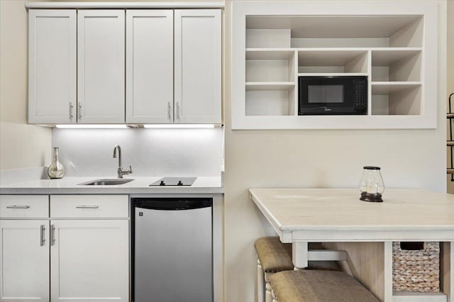 kitchen with white cabinets, sink, black microwave, and stainless steel refrigerator