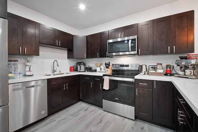 kitchen featuring decorative backsplash, dark brown cabinetry, stainless steel appliances, sink, and light hardwood / wood-style flooring