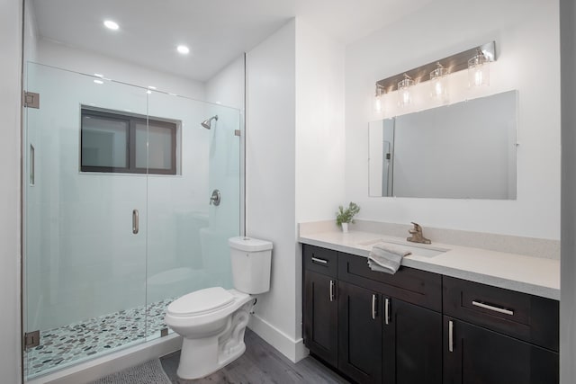 bathroom with toilet, vanity, a shower with shower door, and hardwood / wood-style flooring