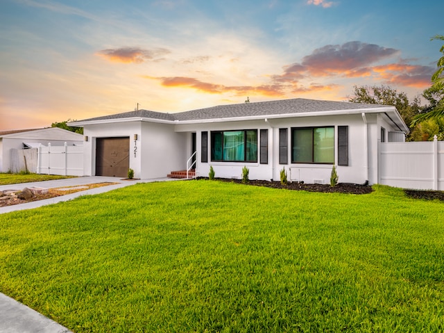 single story home featuring a garage and a yard