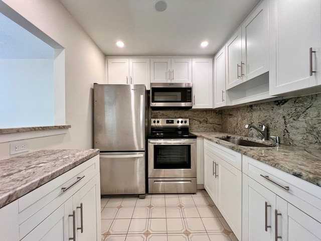 kitchen featuring light stone countertops, tasteful backsplash, stainless steel appliances, sink, and white cabinetry