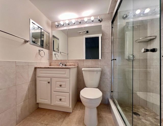 bathroom with tile patterned floors, an enclosed shower, toilet, vanity, and tile walls