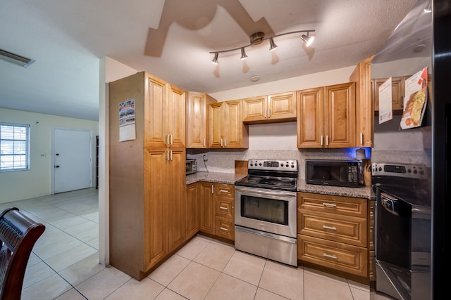 kitchen with light tile patterned floors, electric range, rail lighting, and dark stone counters