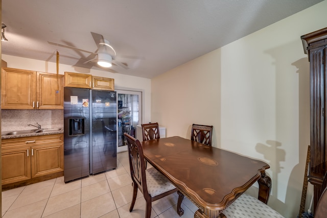 tiled dining area with ceiling fan and sink