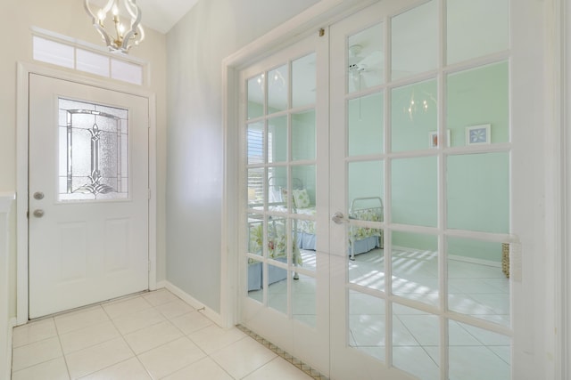 entrance foyer featuring french doors, ceiling fan with notable chandelier, and light tile patterned floors