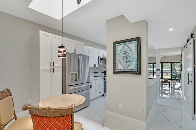 kitchen featuring appliances with stainless steel finishes, a barn door, white cabinetry, and backsplash