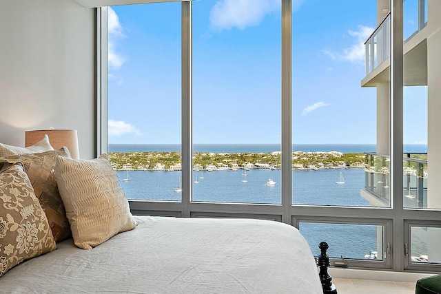 bedroom with expansive windows, multiple windows, and a water view