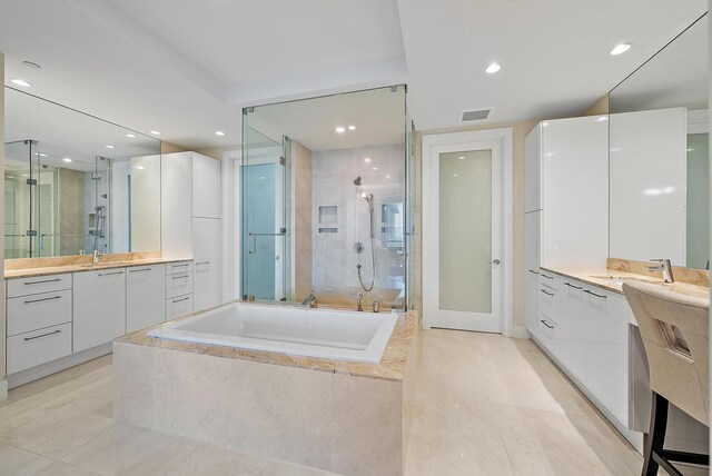 bathroom with visible vents, a shower stall, two vanities, and a sink