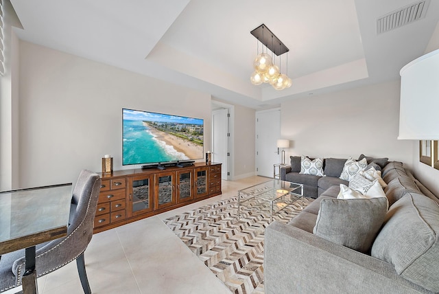 living room featuring light tile patterned floors, visible vents, a raised ceiling, and baseboards