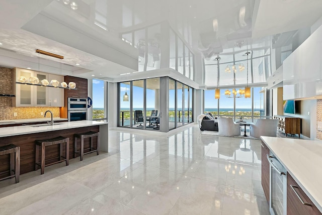 kitchen featuring backsplash, open floor plan, light countertops, an inviting chandelier, and a sink