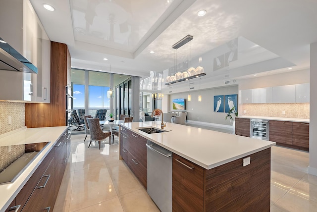 kitchen with pendant lighting, a raised ceiling, white cabinetry, and a large island with sink