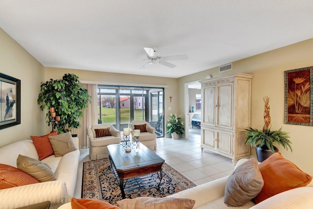 living room with a textured ceiling, ceiling fan, and light tile patterned flooring