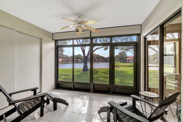 sunroom with ceiling fan, plenty of natural light, and a water view