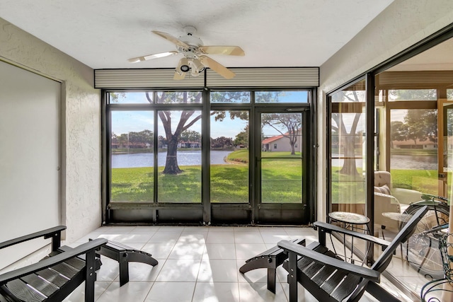 sunroom with ceiling fan and a water view