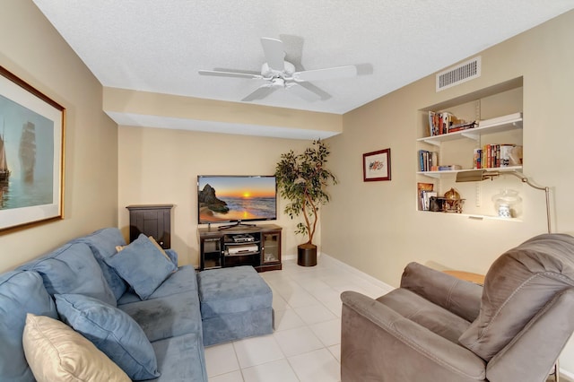 living room featuring ceiling fan, light tile patterned floors, and a textured ceiling