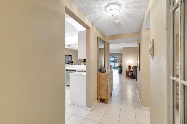 corridor with light tile patterned floors and a textured ceiling