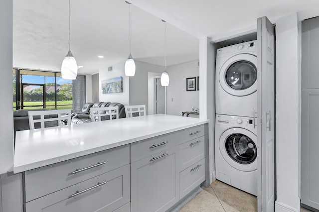 clothes washing area featuring stacked washer / drying machine and light tile patterned flooring