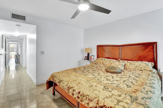 tiled bedroom with a textured ceiling and ceiling fan