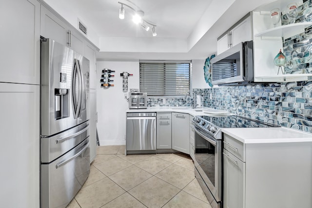 kitchen featuring gray cabinetry, sink, stainless steel appliances, backsplash, and light tile patterned floors