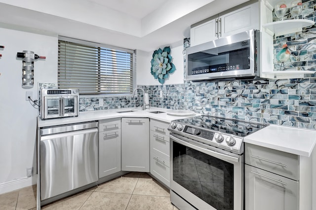 kitchen featuring gray cabinetry, sink, decorative backsplash, light tile patterned floors, and appliances with stainless steel finishes