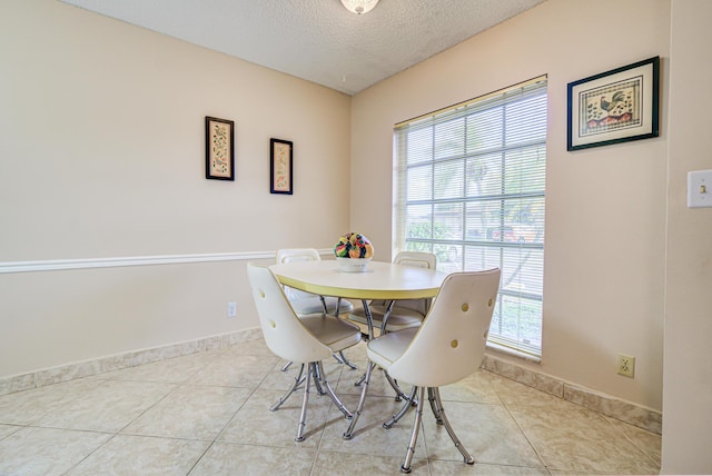 dining area featuring light tile patterned floors and a textured ceiling