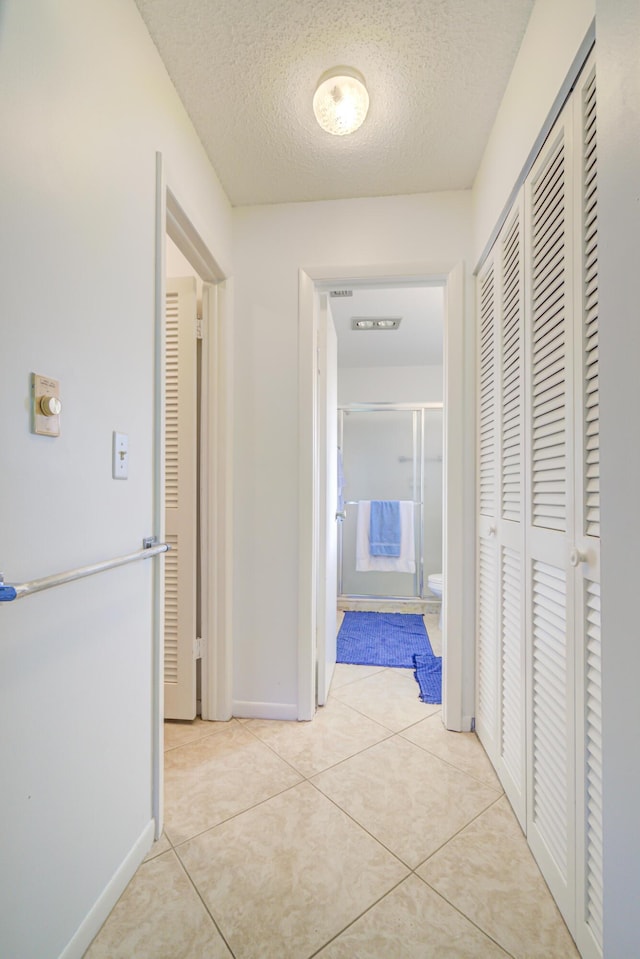 corridor with light tile patterned flooring and a textured ceiling