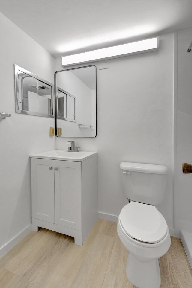 bathroom with toilet, vanity, and hardwood / wood-style flooring