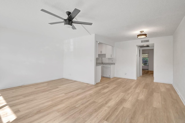 unfurnished living room with ceiling fan, a textured ceiling, and light hardwood / wood-style flooring