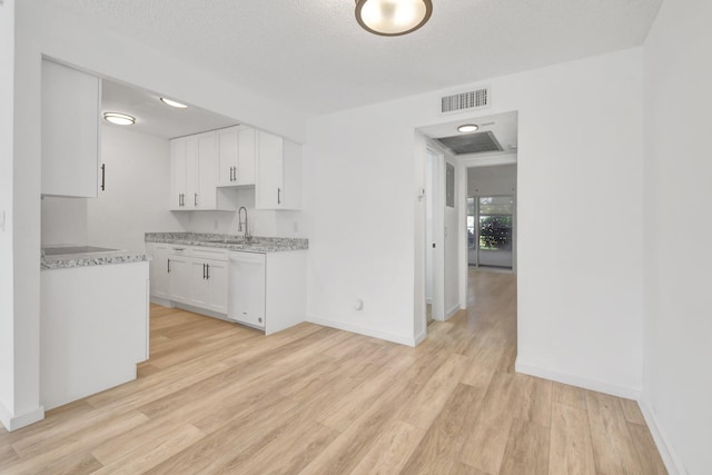 kitchen featuring white cabinets, dishwasher, light wood-type flooring, and a textured ceiling