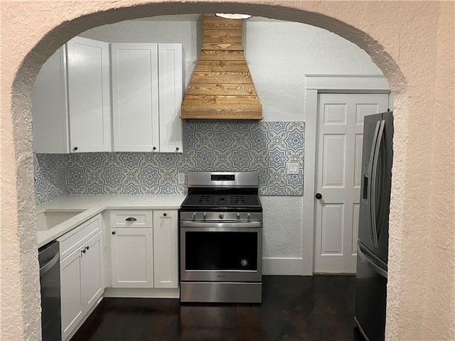 kitchen with stainless steel appliances, white cabinetry, tasteful backsplash, and range hood