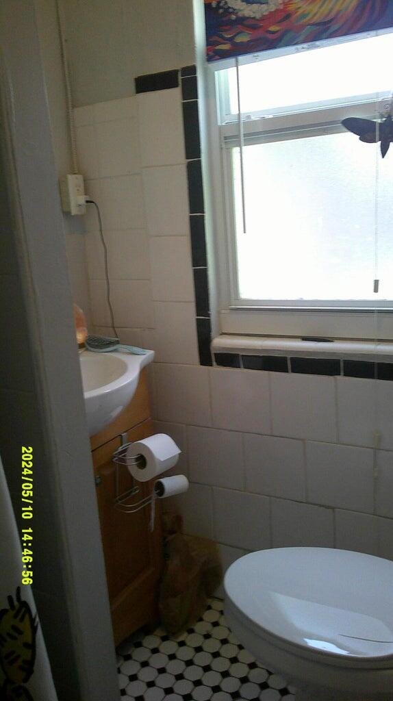 bathroom featuring toilet, sink, and tile walls