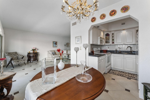 dining space with light tile patterned floors, a notable chandelier, and sink