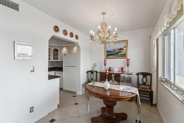 dining room featuring a notable chandelier, light tile patterned flooring, and a textured ceiling