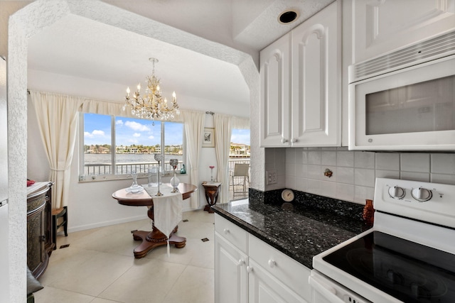 kitchen with white cabinets, light tile patterned floors, white appliances, and backsplash