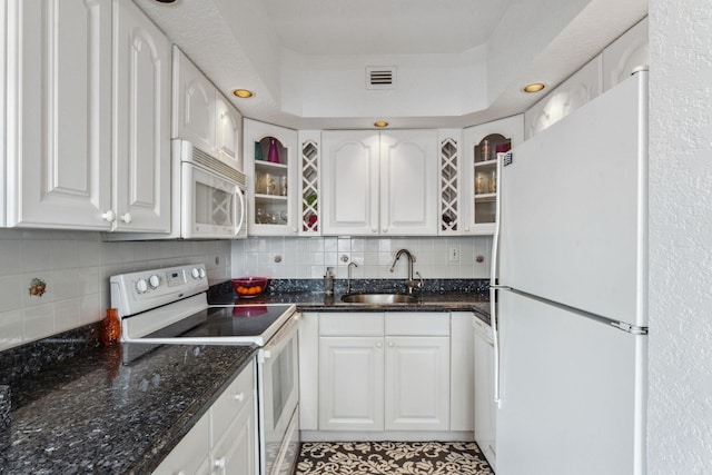 kitchen featuring white appliances, white cabinets, sink, decorative backsplash, and dark stone countertops