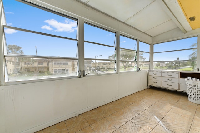 unfurnished sunroom featuring lofted ceiling with beams