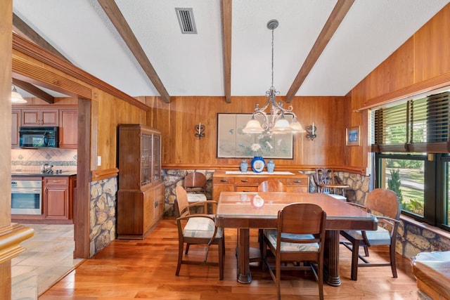 5405 Duckweed Rd, Wellington, FL 33449 - dining space featuring lofted ceiling with beams, wood walls, light wood-type flooring, and an inviting chandelier