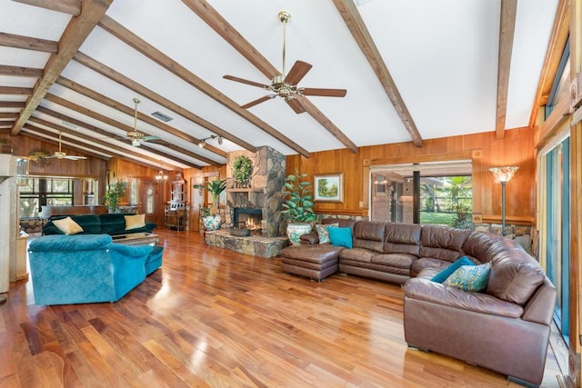 5405 Duckweed Rd, Wellington, FL 33449 - living room featuring beam ceiling, ceiling fan, a stone fireplace, wood-type flooring, and wooden walls