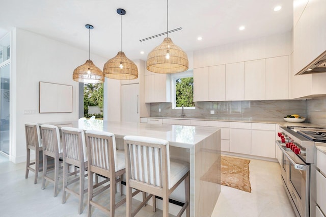 kitchen with tasteful backsplash, white cabinets, a kitchen island, and range with two ovens