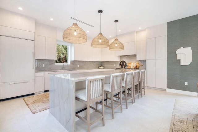 kitchen featuring white cabinets, a kitchen breakfast bar, a center island, and decorative light fixtures