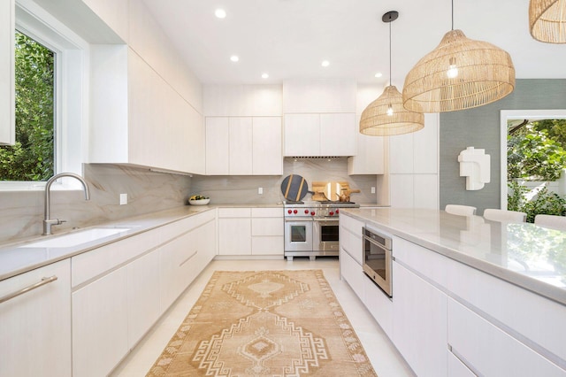 kitchen featuring decorative backsplash, appliances with stainless steel finishes, sink, decorative light fixtures, and white cabinets