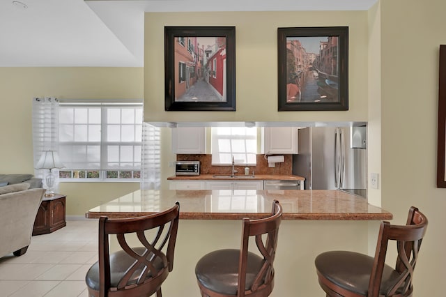 kitchen with a breakfast bar area, white cabinetry, sink, and appliances with stainless steel finishes