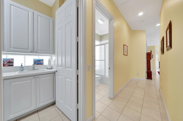 hall featuring light tile patterned flooring and sink