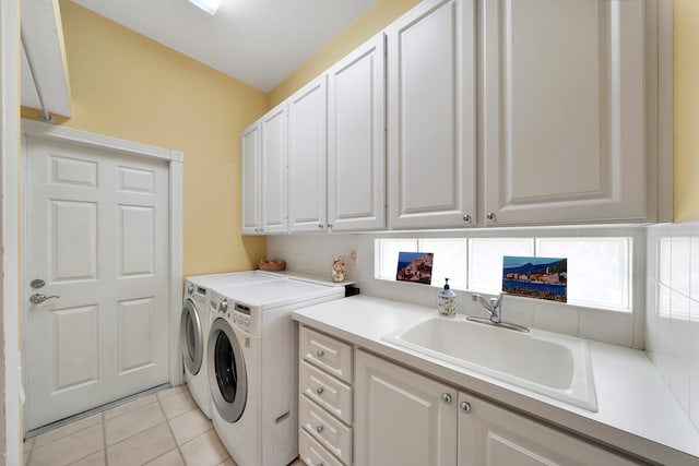 clothes washing area with cabinets, light tile patterned floors, sink, and washing machine and dryer