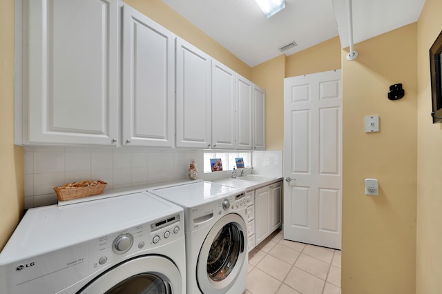 washroom with washing machine and clothes dryer, sink, light tile patterned floors, and cabinets