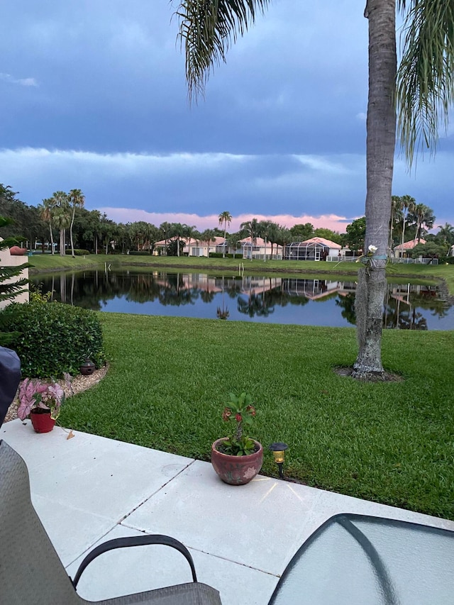 yard at dusk featuring a water view