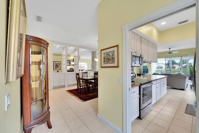 kitchen with ceiling fan, white cabinets, light tile patterned floors, and appliances with stainless steel finishes