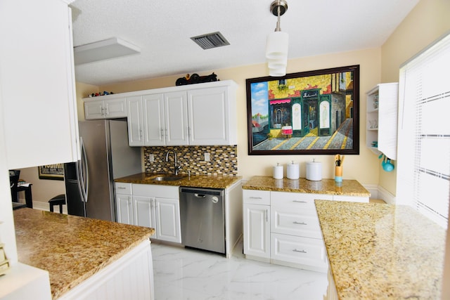 kitchen with appliances with stainless steel finishes, backsplash, sink, decorative light fixtures, and white cabinetry