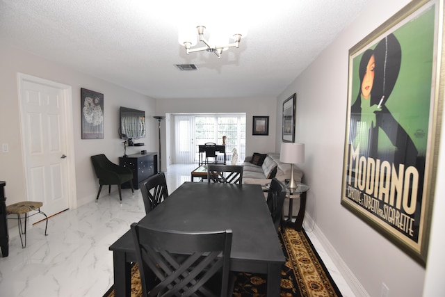 dining area with a chandelier and a textured ceiling